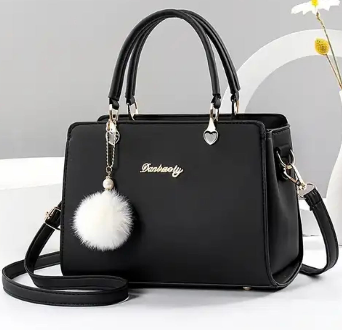 Fashionable handbag with decorative pompom