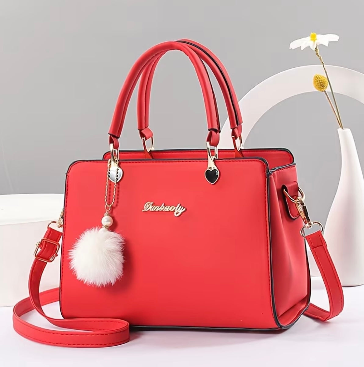 Fashionable handbag with decorative pompom