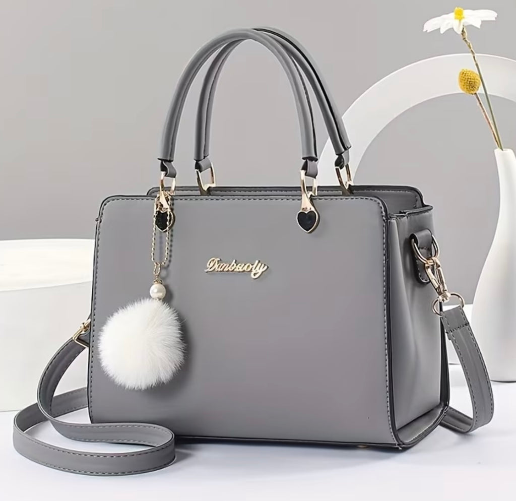 Fashionable handbag with decorative pompom