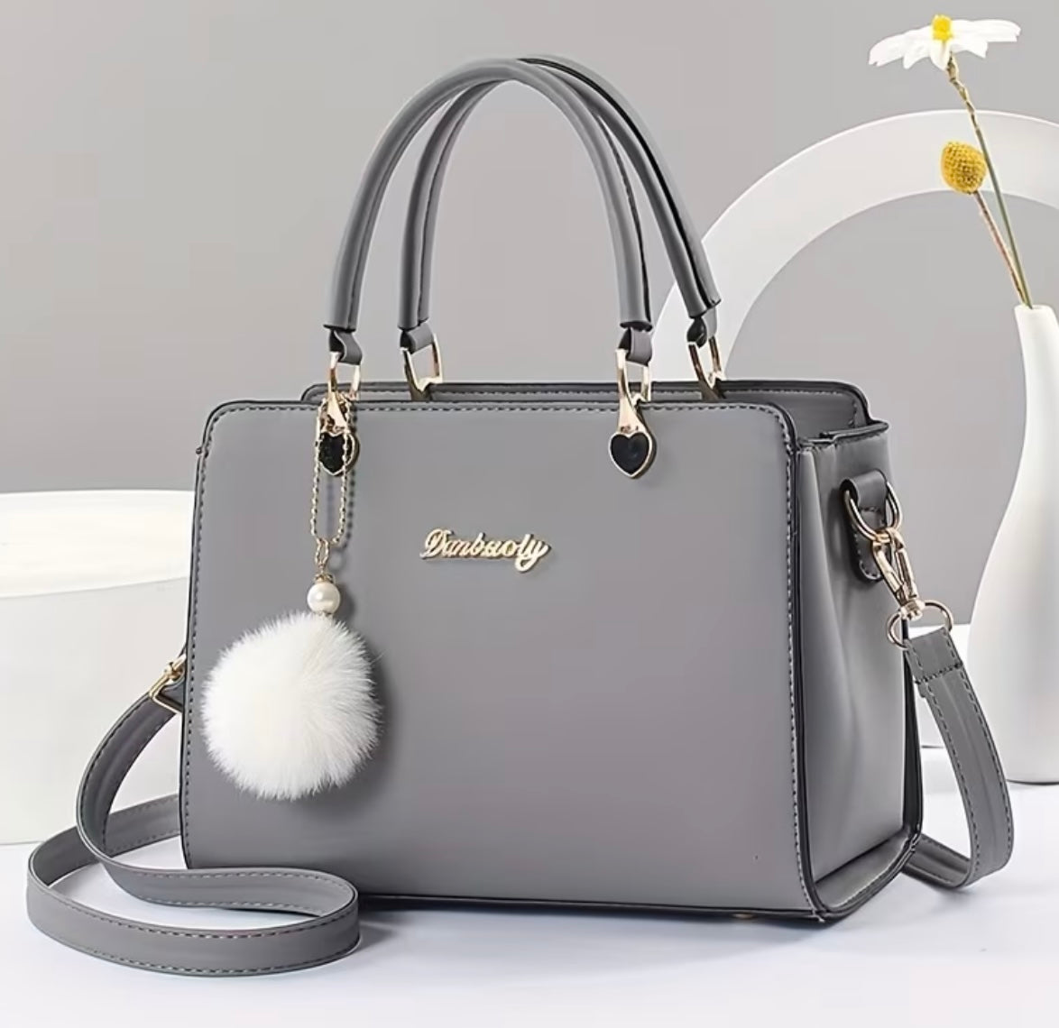 Fashionable handbag with decorative pompom